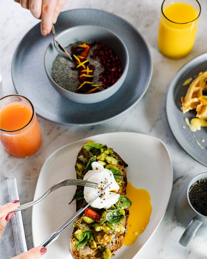 Avocado toast with poached egg, fresh breakfast plates, and juice